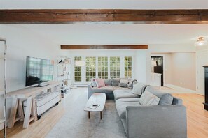 Ein modernes Wohnzimmer mit einem grauen Sofa, einem Holztisch und einem Fernseher auf einem Schrank.