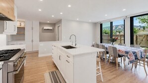 Une cuisine moderne avec des meubles blancs, un îlot central et un coin repas comprenant une table et des chaises.