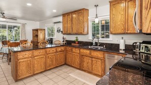 A kitchen with wooden cabinets, a granite countertop, a dishwasher, and a stove. - Yosemite Retreat Near Bass Lake with Firepit, BBQ & Sauna (Oakhurst)