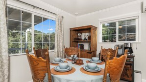 A dining area with a table set for four, surrounded by wooden chairs, with a wooden cabinet and a coffee maker in the background. - Yosemite Retreat Near Bass Lake with Firepit, BBQ & Sauna (Oakhurst)