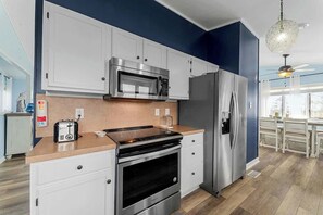 Eine moderne Küche mit Edelstahlgeräten, einer Mikrowelle, einem Backofen und einem Kühlschrank.