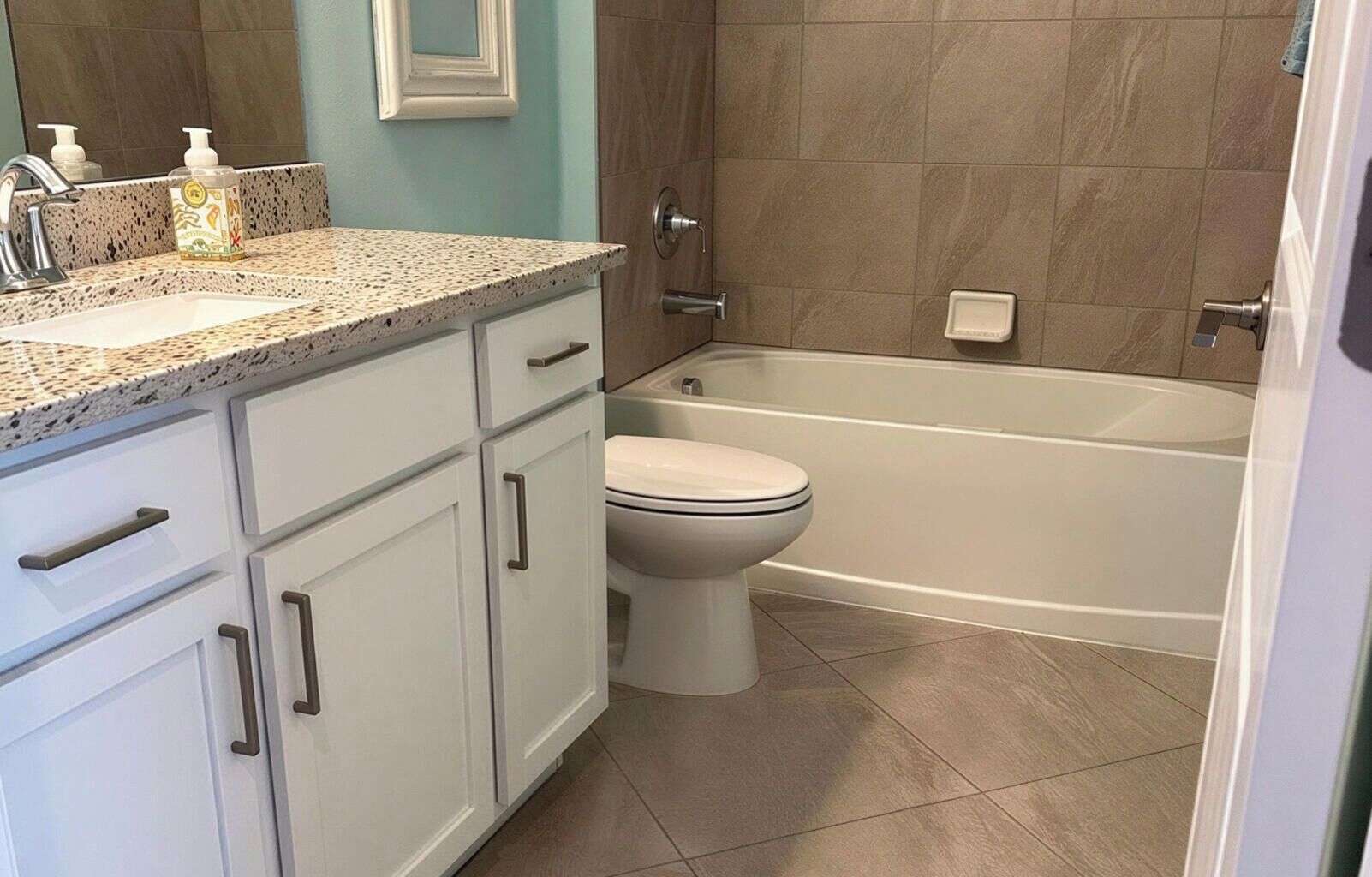 A bathroom with a white toilet, a bathtub, and a sink with a speckled countertop.