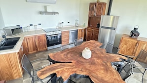 Een moderne keuken met een centraal eiland, roestvrijstalen apparatuur en een eetgedeelte met metalen stoelen.