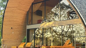 Een modern gebouw met een gebogen houten gevel, grote glasramen en terrasplekken.