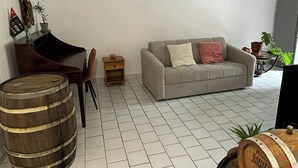 Un salon avec un canapé gris, une table d’appoint en bois et un tonneau en bois.