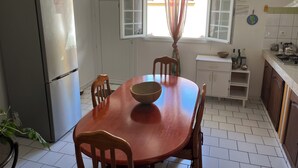 Une cuisine équipée d’une table à manger, de chaises, d’un réfrigérateur, d’une fenêtre avec des rideaux et d’une cuisinière.