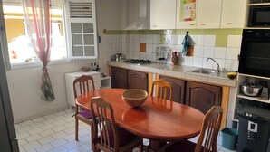 Une cuisine équipée d’une table à manger, de chaises, d’une cuisinière, d’un évier et de placards.