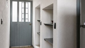 Ein Korridor mit einer grauen Tür, Fliesenboden und eingebauten Regale.