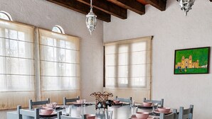 Ein Essbereich mit einem für sechs Personen gedeckten Tisch, Holzstühlen und hängenden Pendelleuchten.