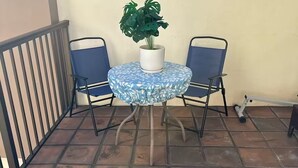 A round table with a blue floral tablecloth, two blue chairs, and a potted plant. - Unique Bishop Loft (Honolulu)