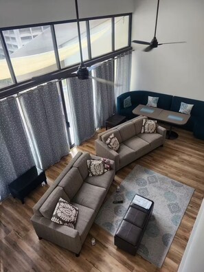 Ein modernes Wohnzimmer mit einem Ecksofa, einem kleinen Tisch und einem Deckenventilator.