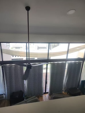 A room with a large window, a ceiling fan, and a view of an outdoor area. - Unique Bishop Loft (Honolulu)