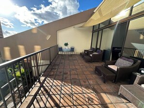 Ein Balkon mit gefliestem Boden, einem Tisch mit Stühlen und Korbmöbeln.