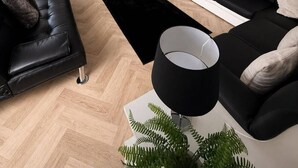 Un salon moderne avec un canapé en cuir noir, une table basse noire et blanche, un lampadaire noir et un téléviseur posé sur un meuble blanc.