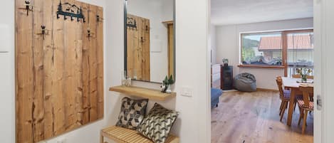 A room with a wooden wall, a mirror, a bench, and a dining area with a table and chairs.