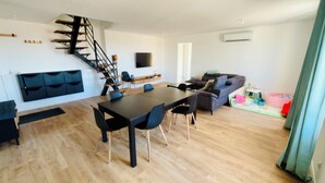 Un saló modern amb escala, zona de menjador i sofà.
