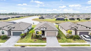 A residential area with modern houses, a curved driveway, and a river in the background. - The Sunset House - Bright, Coastal, Pond View, Amenities and Close to Beaches (Port Charlotte)