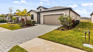 Ein modernes, zweistöckiges Haus mit Garage, befestigter Auffahrt und angelegtem Garten.
