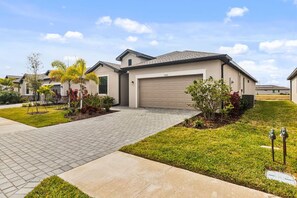 Ein modernes, zweistöckiges Haus mit Garage, befestigter Auffahrt und angelegtem Garten.