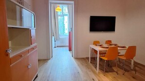 Ein kompakter Wohnbereich mit Küchenzeile, Essbereich und einem an der Wand befestigten Fernseher.