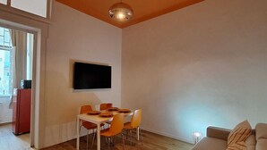 Ein modernes Wohnzimmer mit Essbereich, einem an der Wand befestigten Flachbildfernseher und einem roten Teppich.