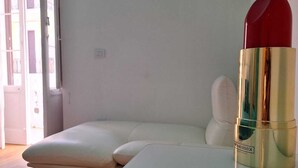 Ein modernes Zimmer mit einem weißen Sofa, einem Glastisch und einem Lippenstift auf dem Tisch.