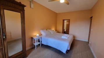 Un dormitorio con cama, mesita de noche y un espejo grande.