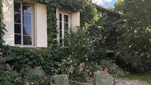 Casa con patio jardín que tiene tres sillas de metal y suelo de grava.