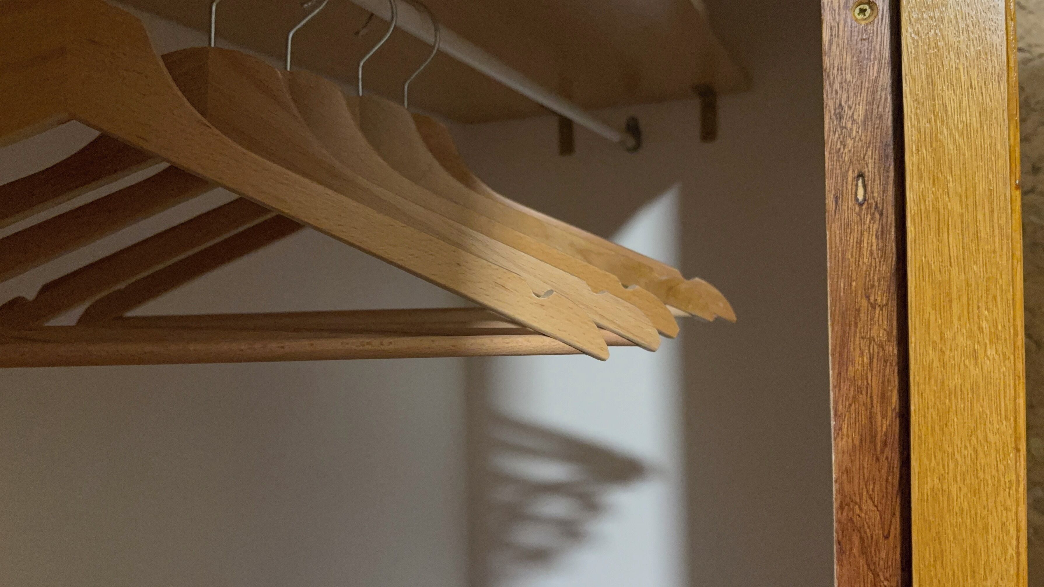 Un porte-manteau en bois muni de plusieurs cintres.