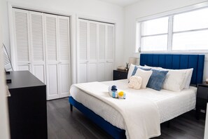 A bedroom with a bed, a desk, a wardrobe, and a window.