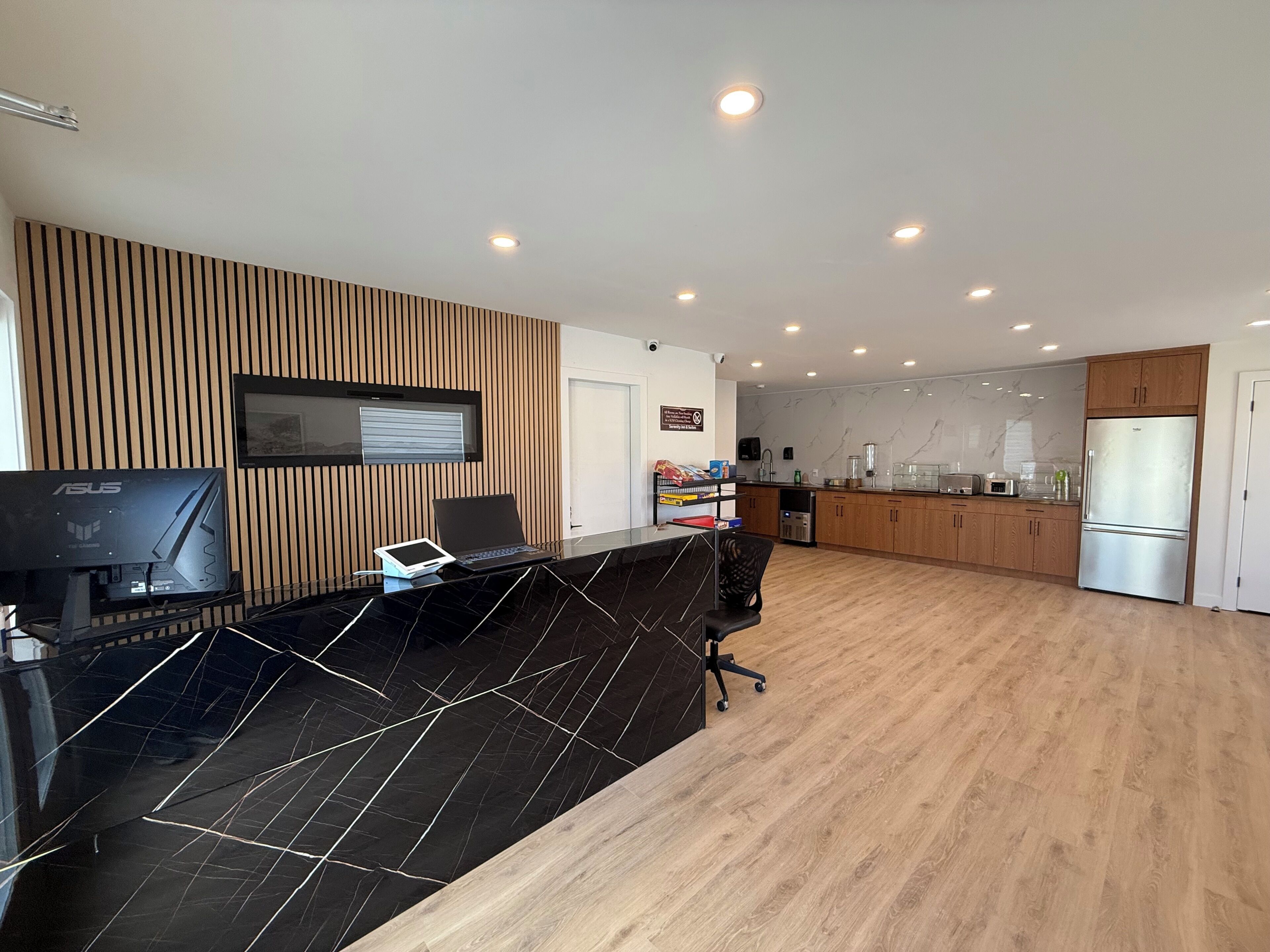 A modern kitchen with a black countertop, wooden panel wall, and a built-in oven.