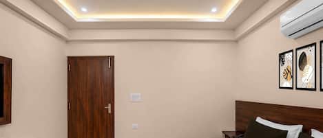 Une chambre d’hôtel comprenant un lit, des tables de chevet, une armoire et un luminaire au plafond.