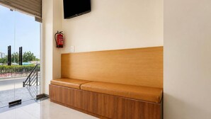 A clean, modern waiting area with a bench, a fire extinguisher, and a flat-screen TV mounted on the wall.