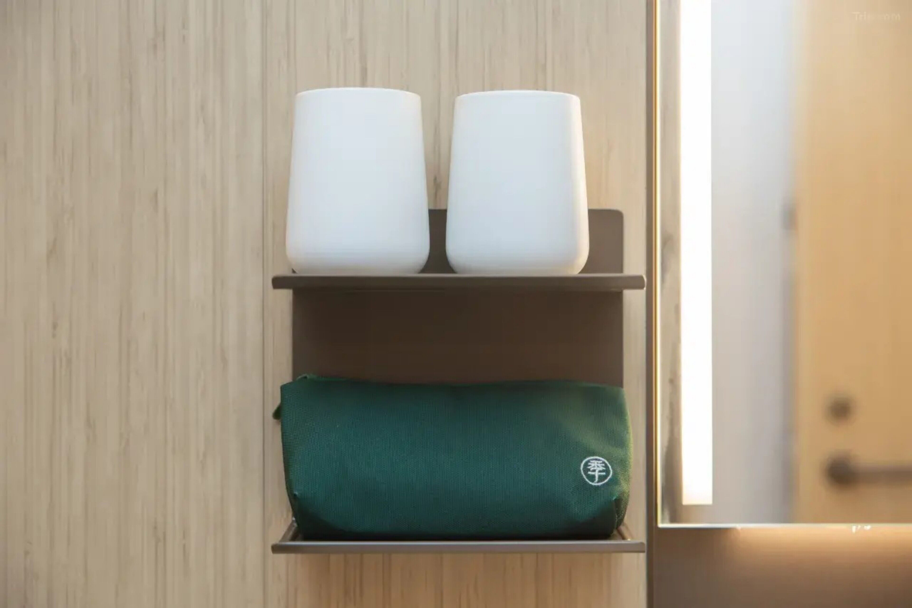 Un estante con dos objetos cilíndricos blancos y un artículo rectangular verde.