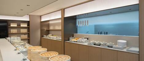 A modern breakfast buffet with a long counter, wooden baskets, and neatly arranged food items.