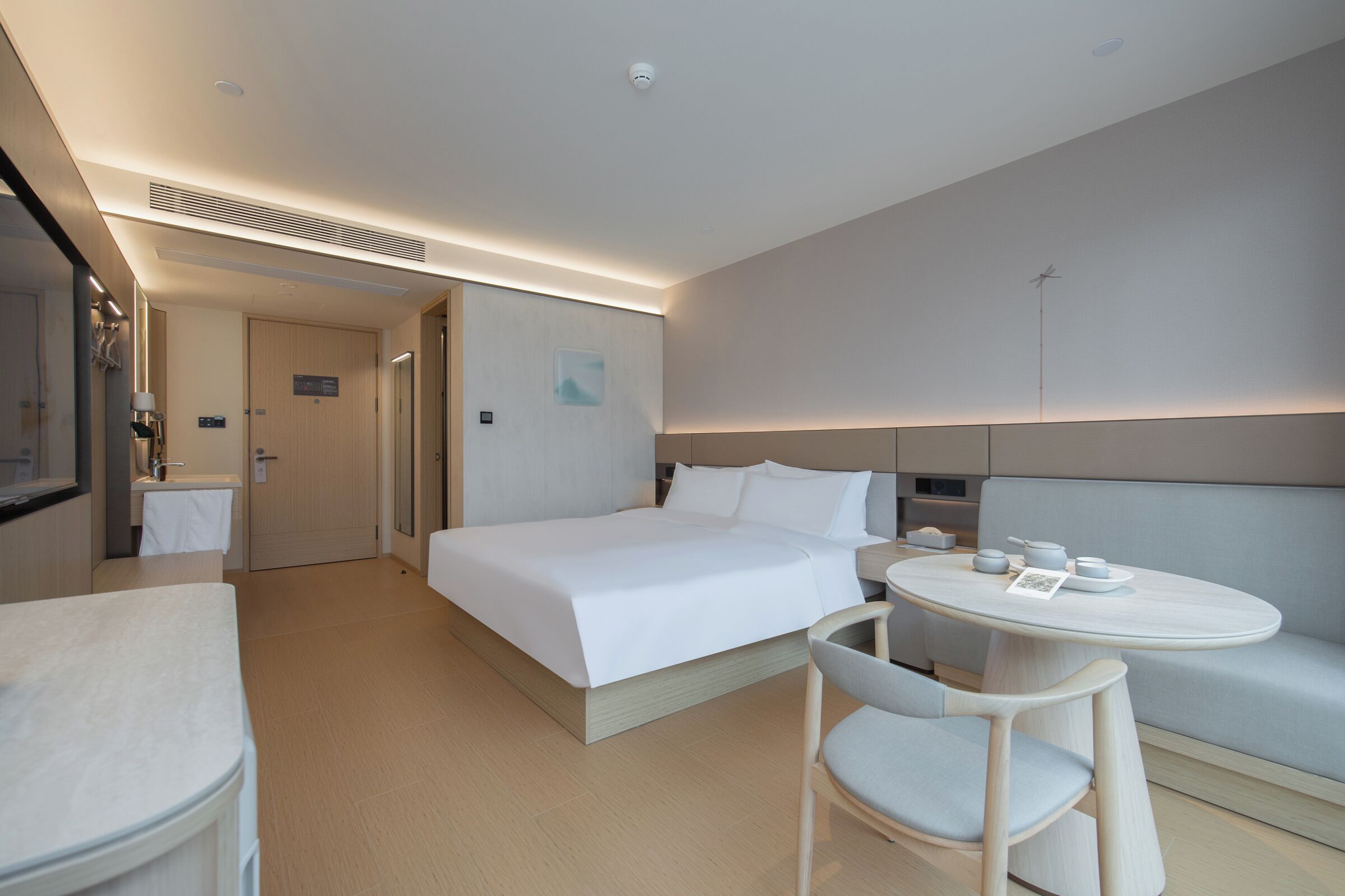 Een hotelkamer met een bed, een ronde tafel met stoelen, een bank en een kleine kitchenette.