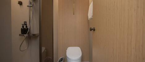 Un bagno moderno con doccia, WC e cestino.