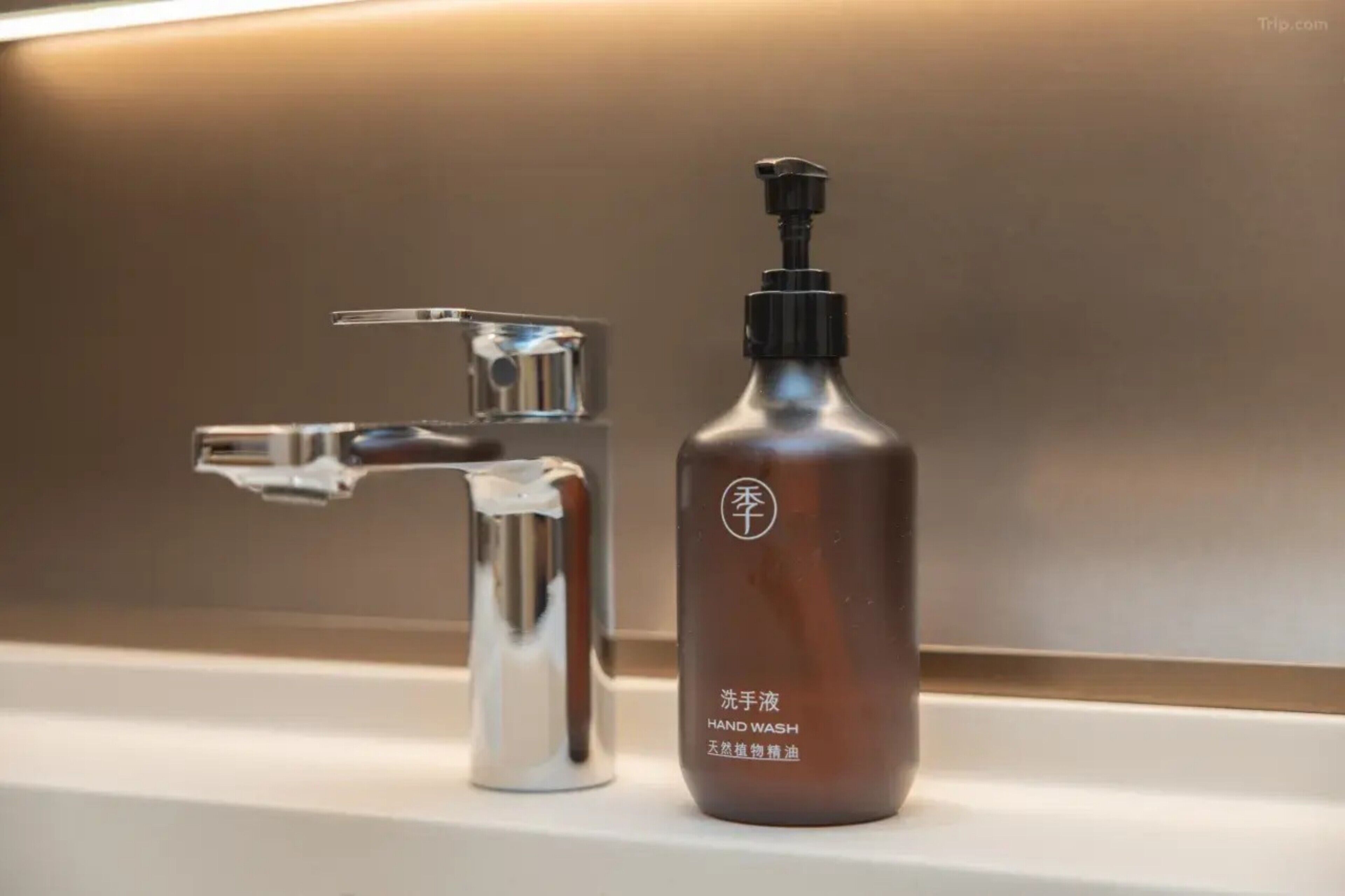 A bathroom with a modern faucet and a bottle of hand wash soap.