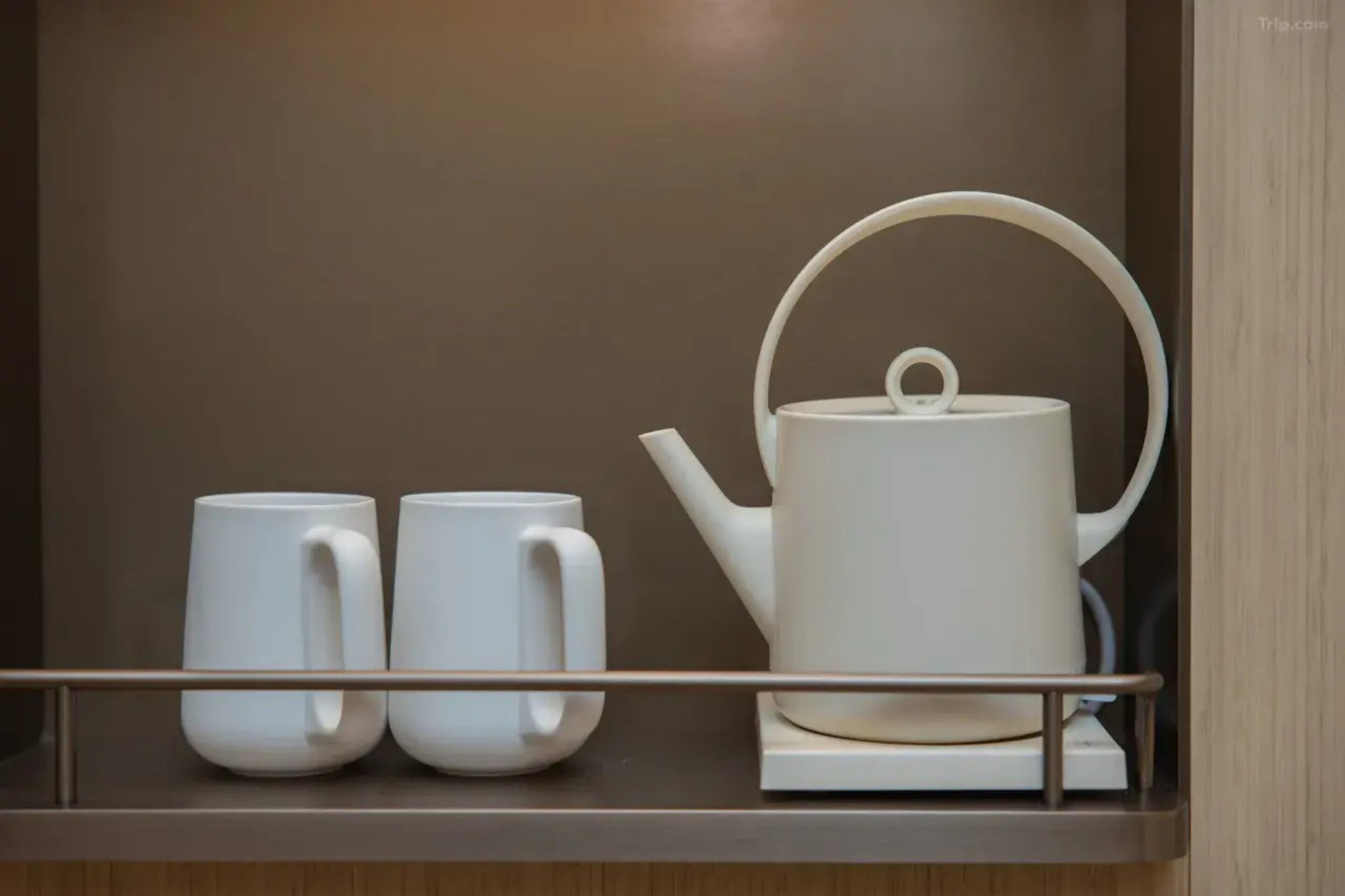A white teapot and two white mugs on a tray.