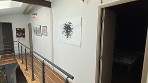Et moderne interiør med en trappe i træ, et ovenlys og en gang der fører til et soveværelse.