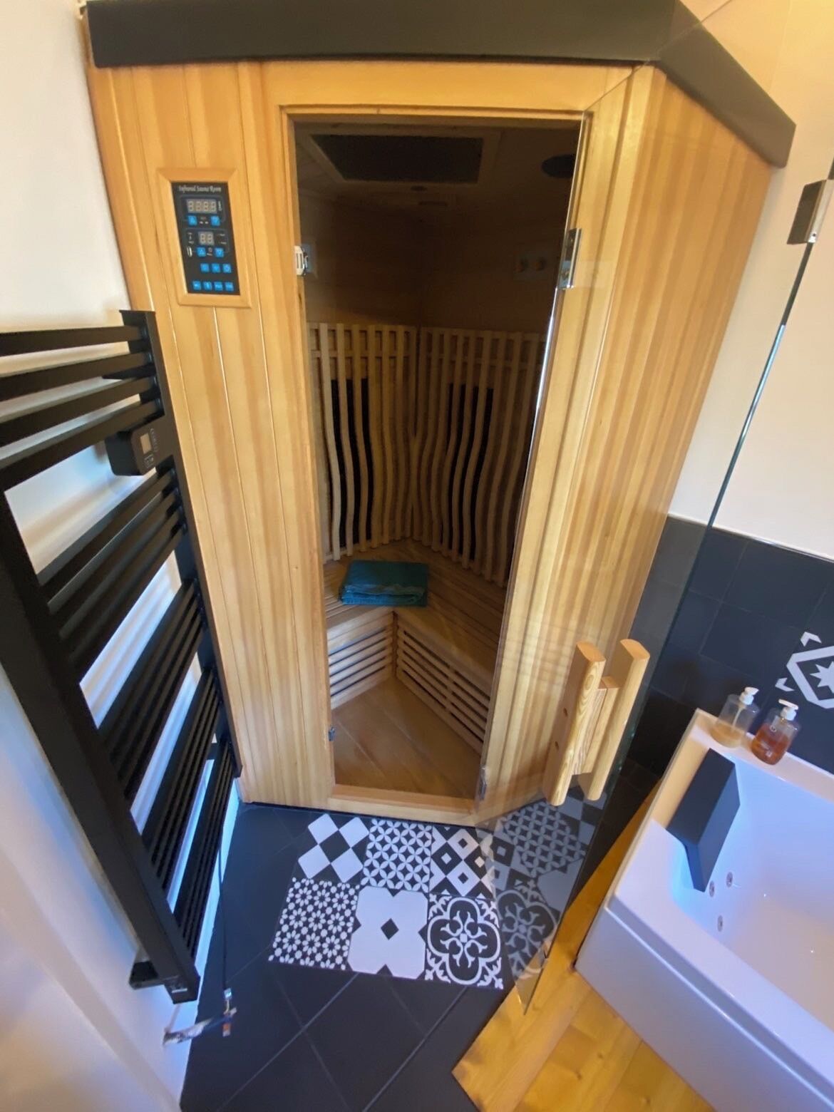 Un sauna avec un intérieur en bois, un panneau de commande et un sol à motifs.