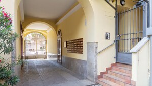 Fachada de edificio con una puerta de metal, una escalera y un buzón fijado a la pared.
