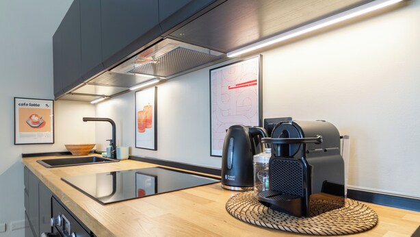 Una cocina moderna con estufa integrada, cafetera y lavaplatos.