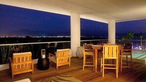 Een houten terras met een tafel, stoelen, een grote vaas en een lantaarn.