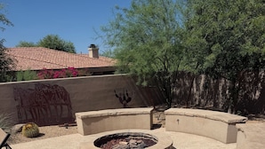 Un patio con una fogata, asientos y un muro decorativo.