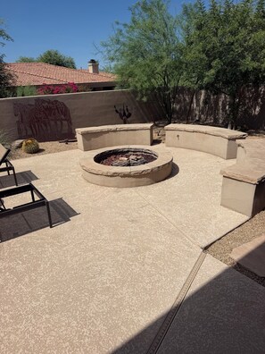 Ein Patio-Bereich mit Feuerstelle, Sitzgelegenheiten und einer Zierwand.