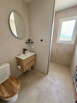 Une salle de bain avec des toilettes, un lavabo, un miroir et une fenêtre.