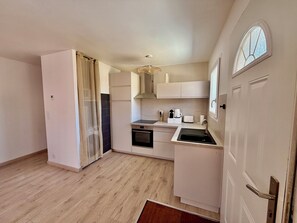 Eine kleine Küche mit Backofen, Spüle und Fenster.
