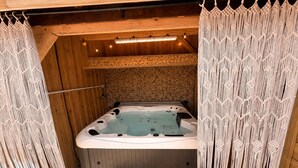 A hot tub with a wooden interior, a wooden bench, and macrame curtains. - La'PaillotteduBassin Vacation Rental (Le Teich)