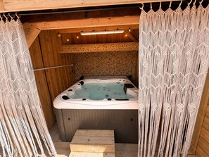 Eine Hot Tub mit Holzinnenraum, einer Holzbank und Makramee-Vorhängen.